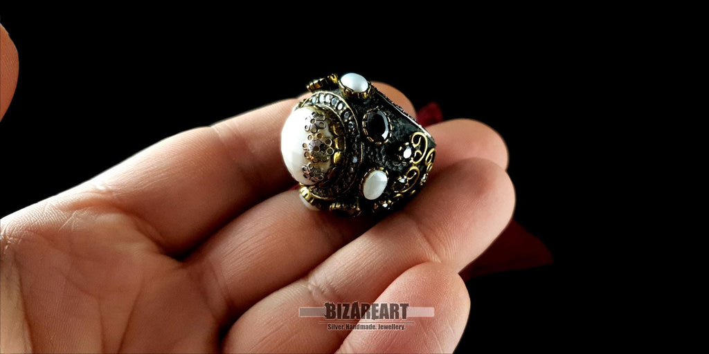 A person holding the artisan white agate dome ring in their hand to showcase its scale and size.