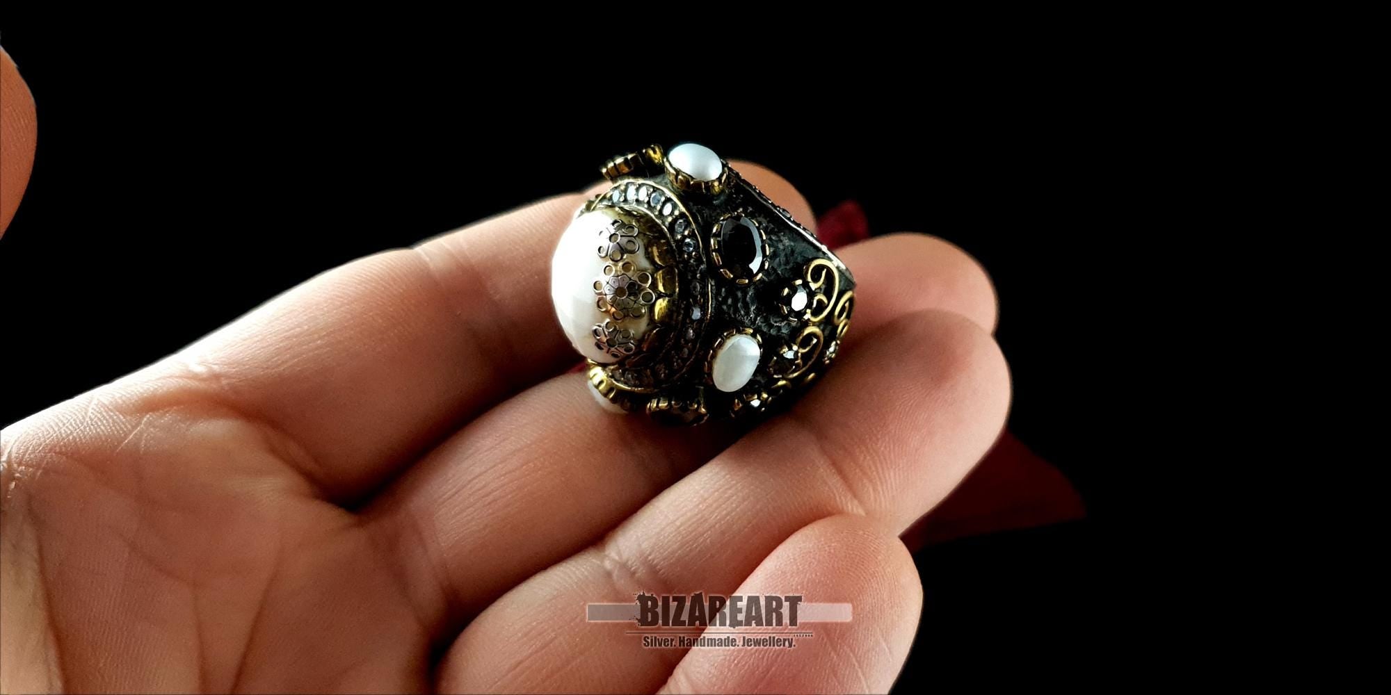 A person holding the artisan white agate dome ring in their hand to showcase its scale and size.