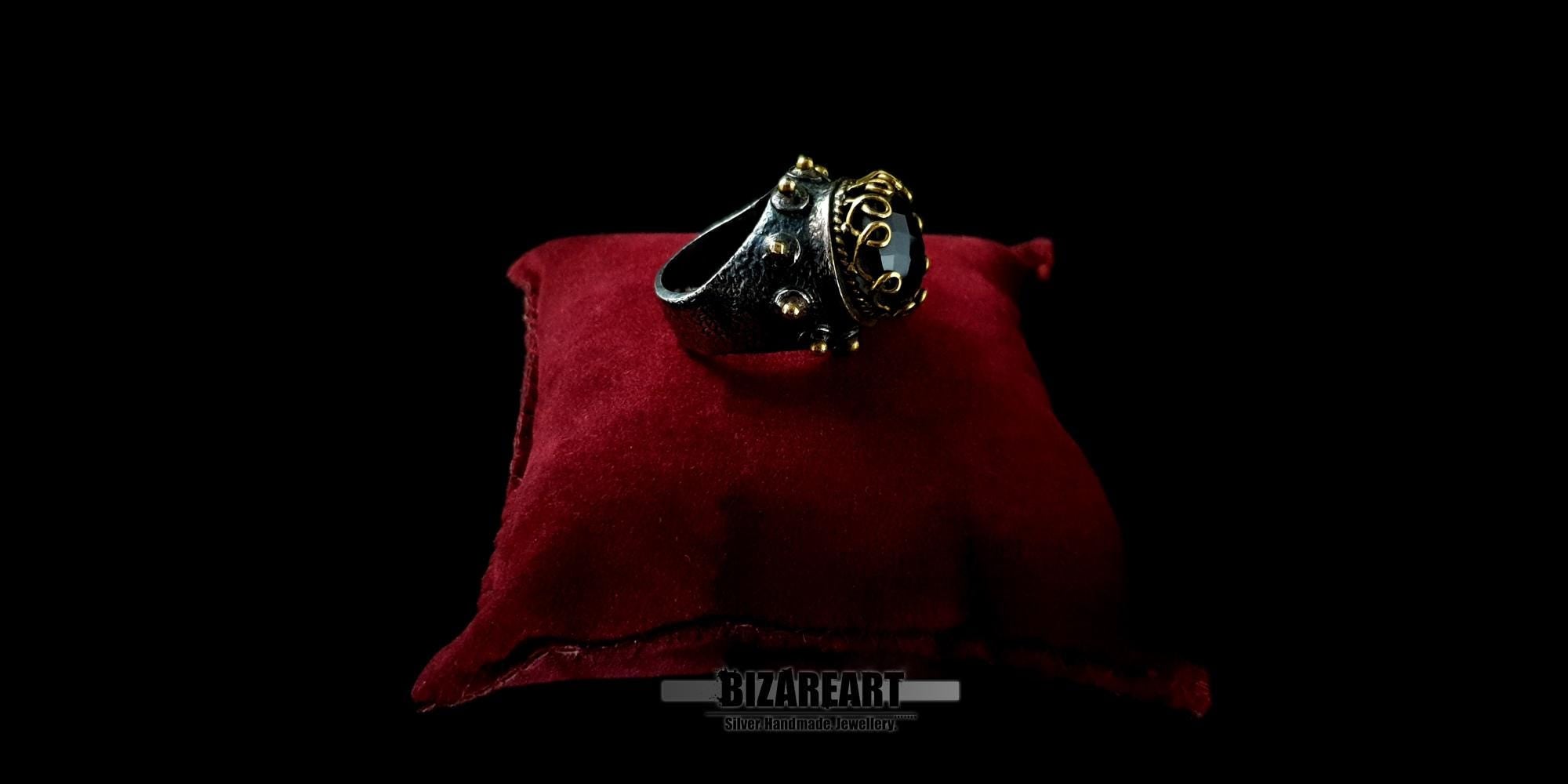 Three-quarter profile view of an artisanal oxidized silver statement ring with a large faceted purple amethyst gemstone.