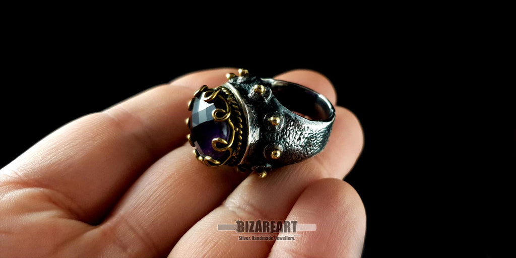 Close-up of a textured, oxidized sterling silver amethyst ring being held to show real-life scale and craftsmanship details.