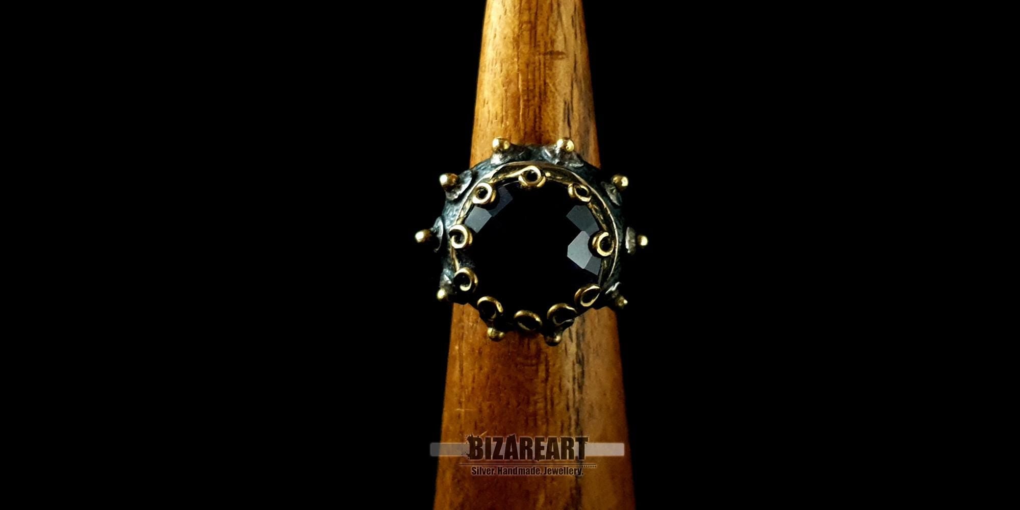 Front-facing view of a handcrafted amethyst statement ring on a wooden display stand, showcasing its intricate crown border.