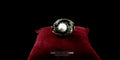 Front view of a statement oxidized silver and gold-plated white agate ring resting on a red velvet cushion.