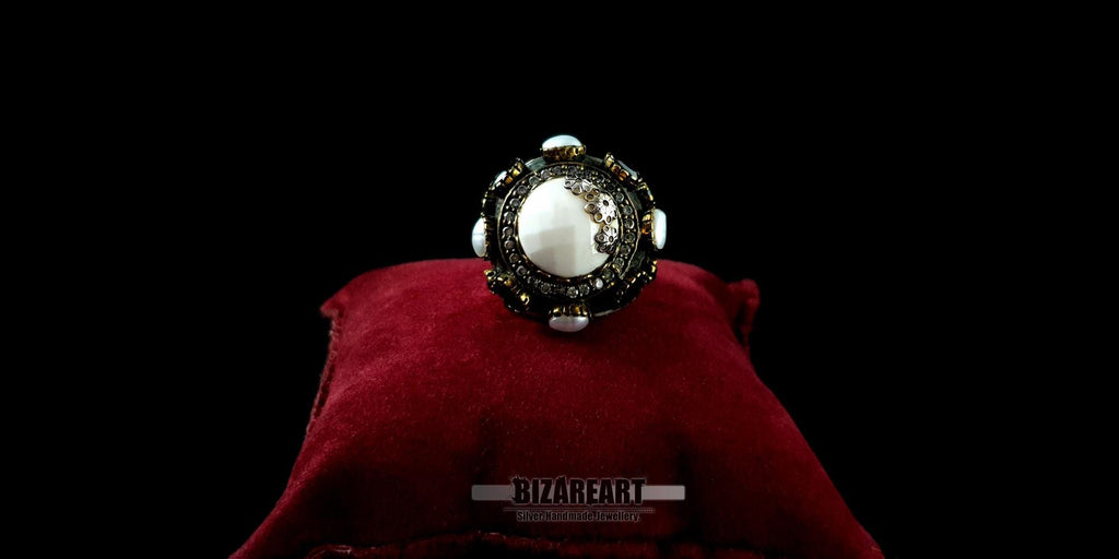 Handcrafted sterling silver white agate dome ring with gold accents displayed on a red velvet pillow.
