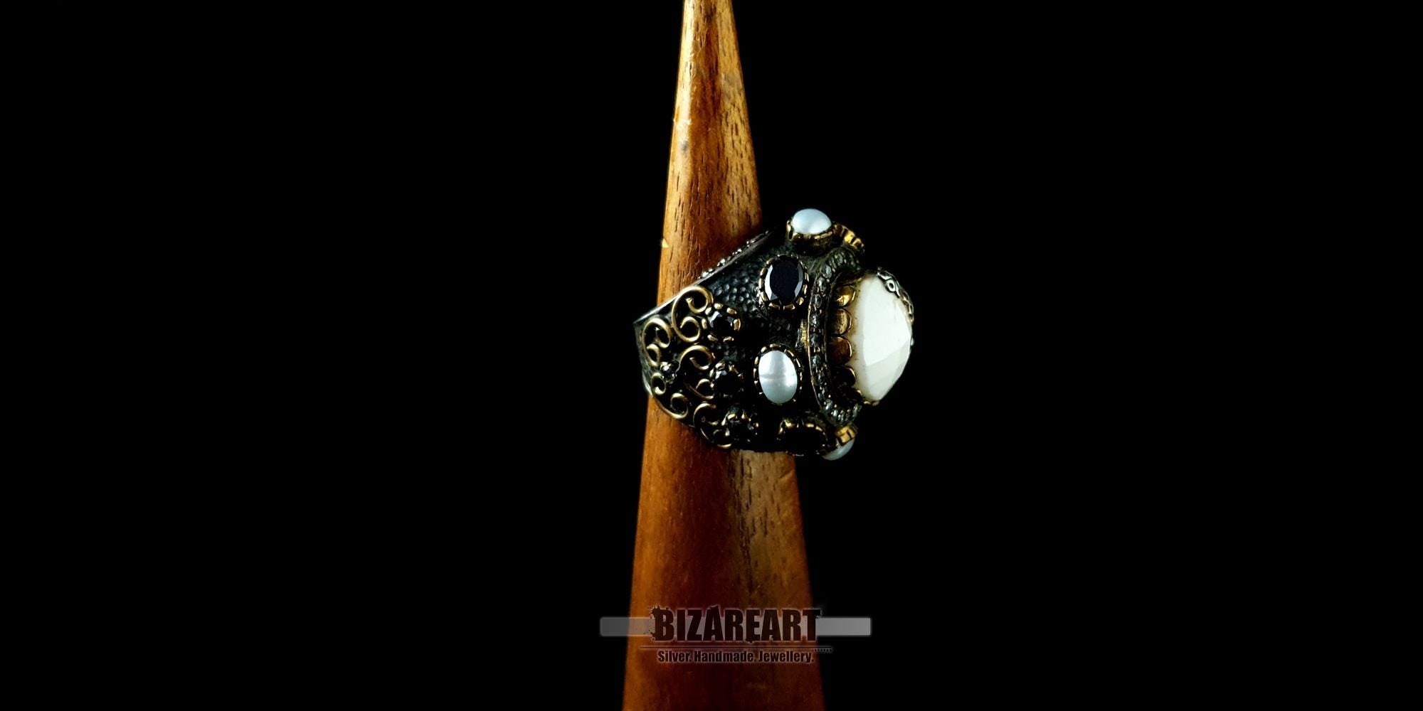 Side-angle view of the white agate and onyx statement ring on a wooden mandrel highlighting its high-contrast texture.