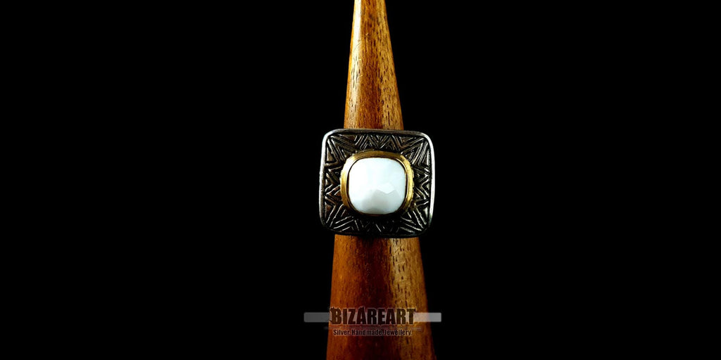 Front view of the square white agate silver ring displayed on a wooden ring cone, highlighting the gold trim contrast and symmetry of the design.