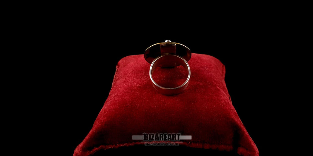 Back view of the ring on a red cushion, displaying the polished silver band and internal construction.