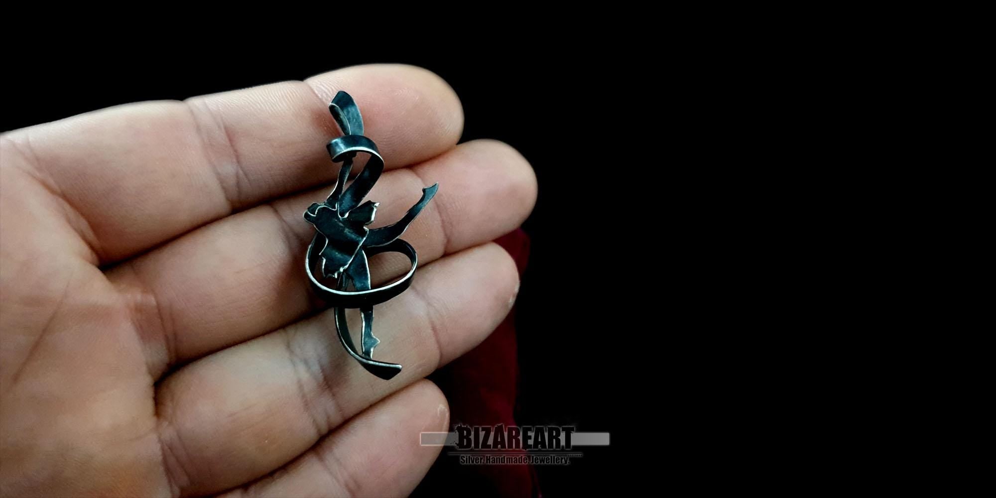 A person holding the 3D ballet dancer pendant in their palm to demonstrate the 5 cm scale and lightweight silver craftsmanship.