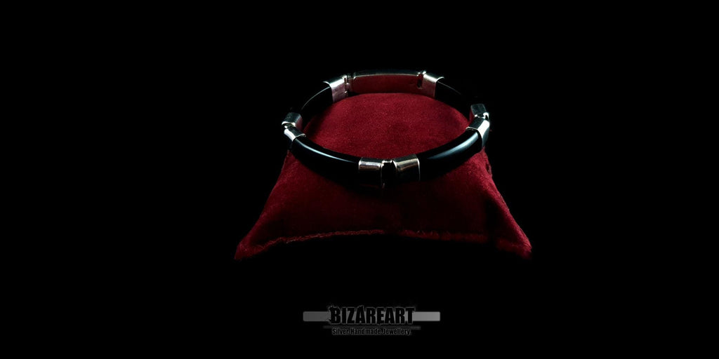 A wide-angle studio shot of the black onyx bracelet on a red display pillow, showcasing its circular profile and polished finish.