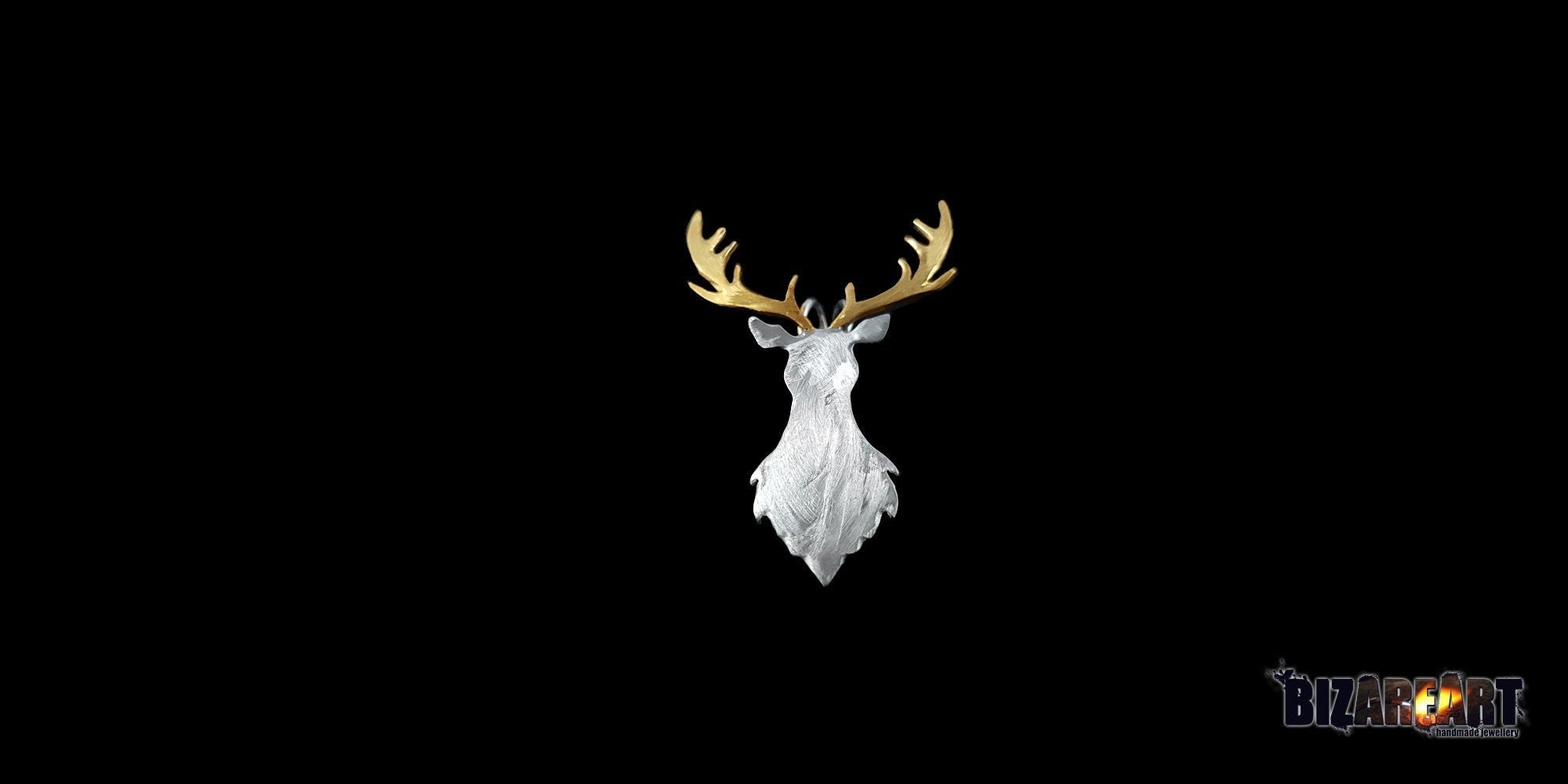 A detailed close-up of a handcrafted deer head pendant on a solid black background. The pendant features a textured white-silver body with contrasting polished gold antlers.