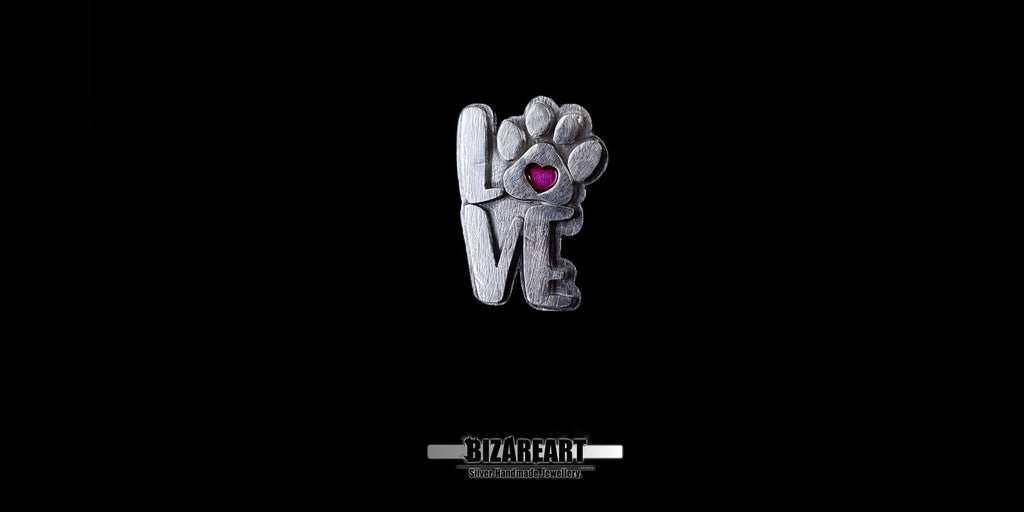 Front-facing view of the silver "LOVE" paw pendant, showcasing the rugged, organic texture of the silver.