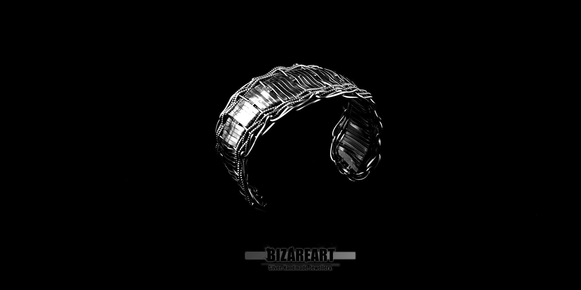 Multilayered silver bracelet with open section, showcasing its intricate woven textured design and bright polished finish against a sleek black background.