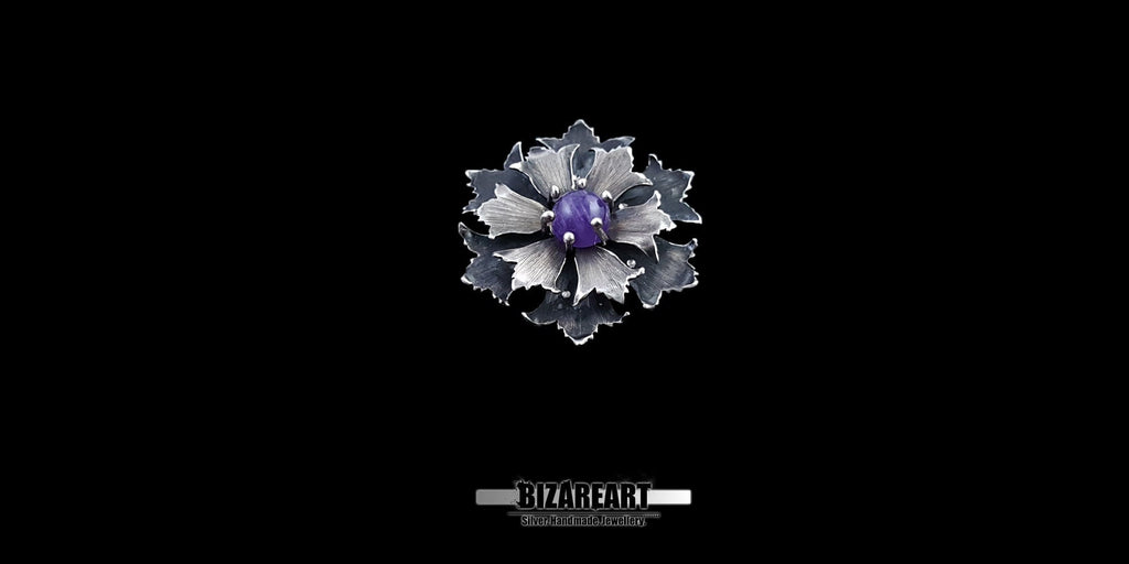 Front studio view of a handcrafted oxidized 925 sterling silver flower pendant with a purple amethyst gemstone center, isolated on a black background.