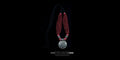 Handcrafted multi-strand red bead necklace with a large round oxidized silver statement pendant, displayed flat on a black background.