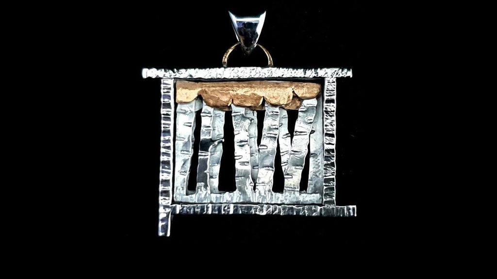 Detailed macro shot of the pendant's facade, highlighting the three-layer silver construction, hand-carved tree textures, and the warm copper hanger at the top.