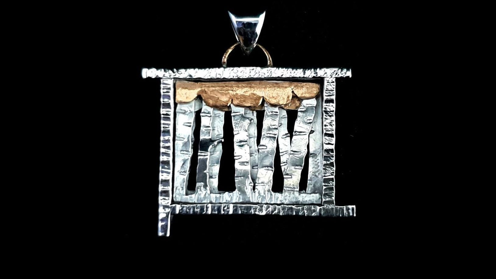 Detailed macro shot of the pendant's facade, highlighting the three-layer silver construction, hand-carved tree textures, and the warm copper hanger at the top.