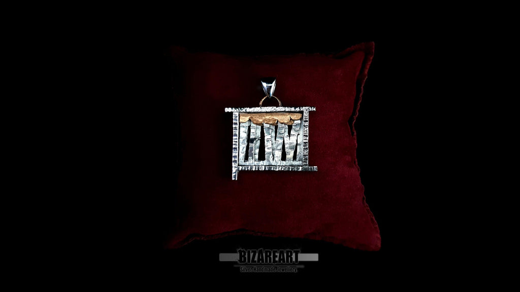 A square, handcrafted sterling silver "forest" pendant with layered metal textures and copper accents, resting on a plush dark red velvet cushion against a black background.