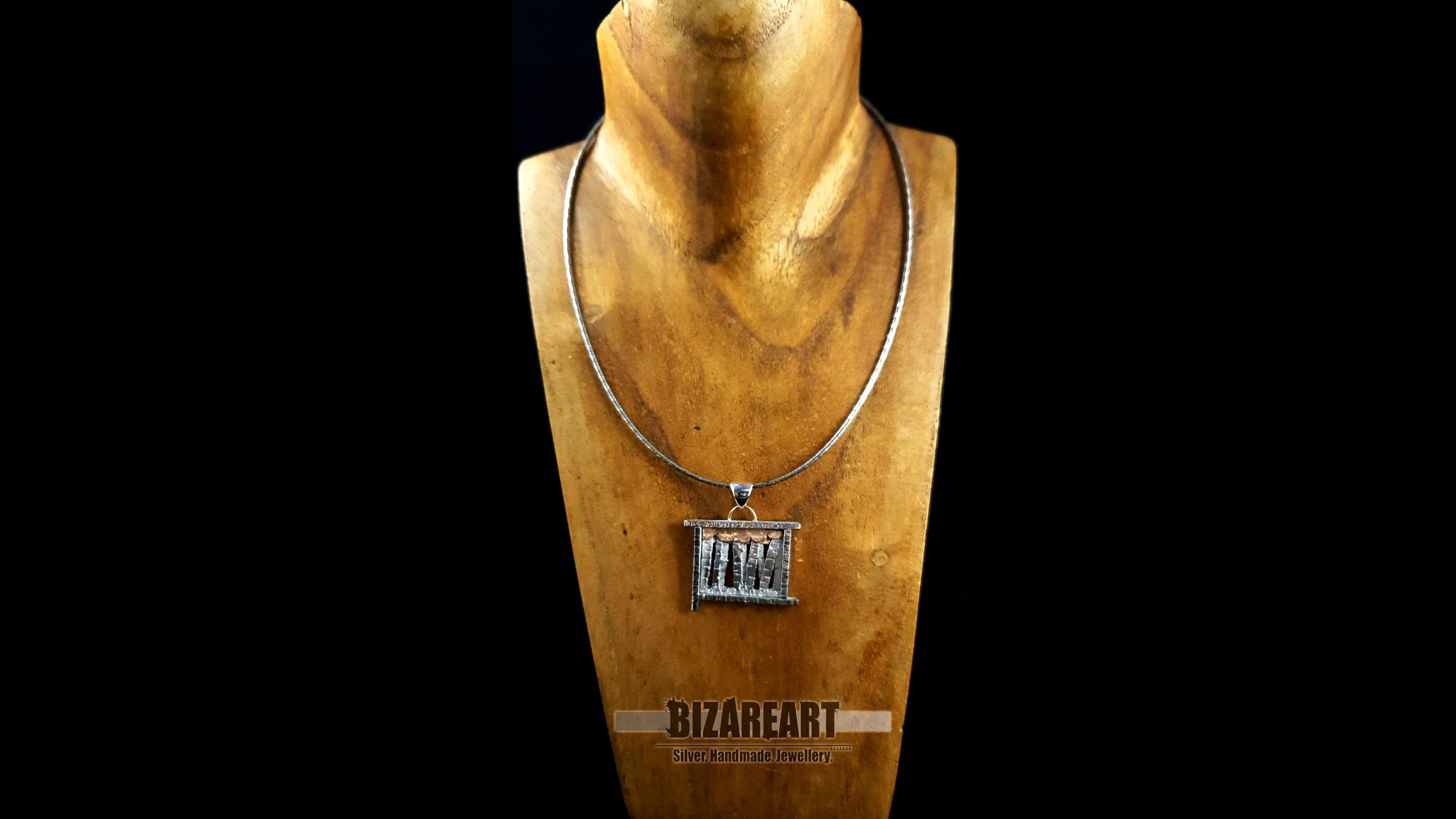 Front view of the silver forest-inspired pendant displayed on a wooden bust, showcasing its size and how it sits at the collarbone.
