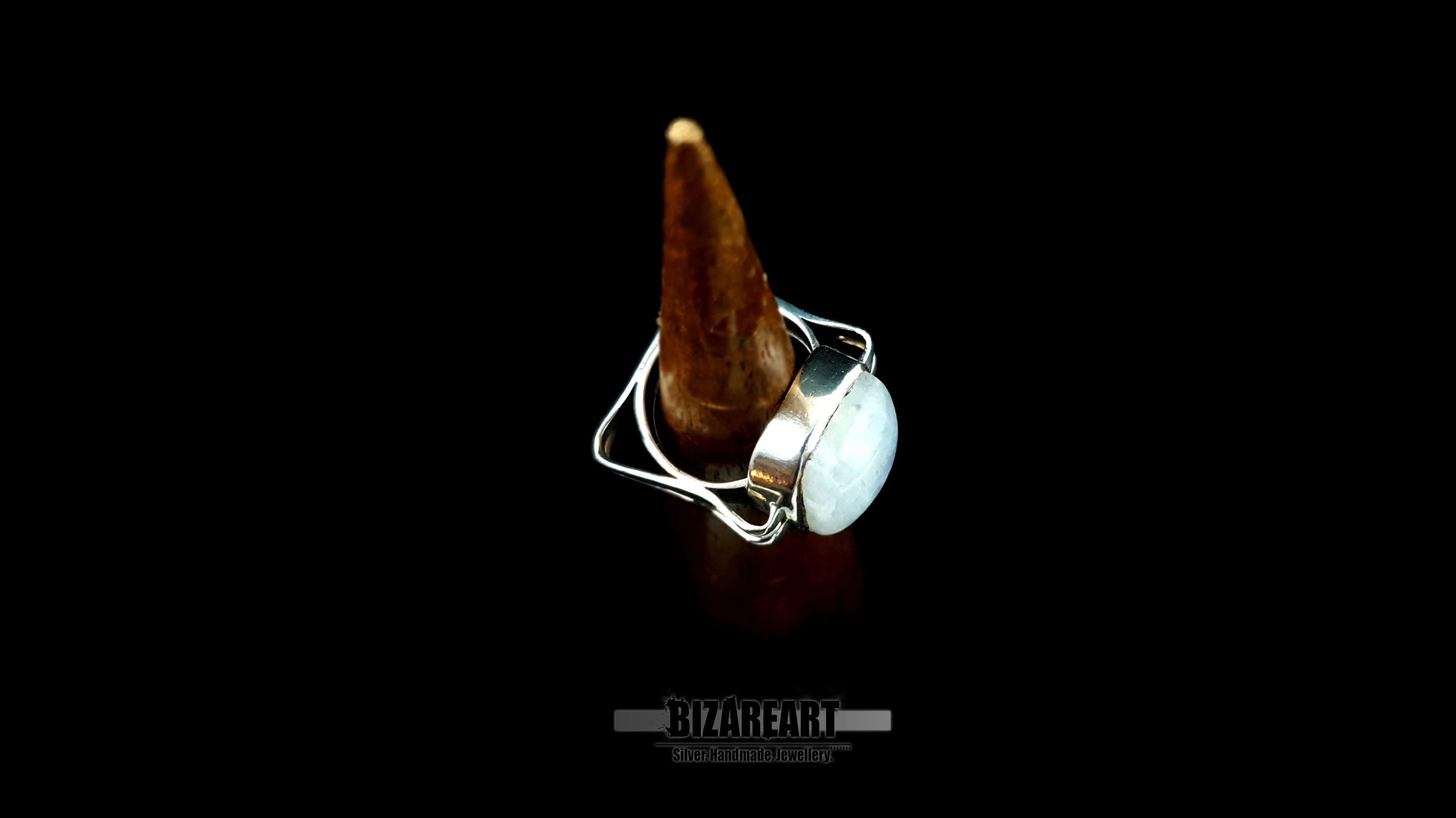 The ring displayed on a wooden ring cone to show the fit and scale of the sculptural design.