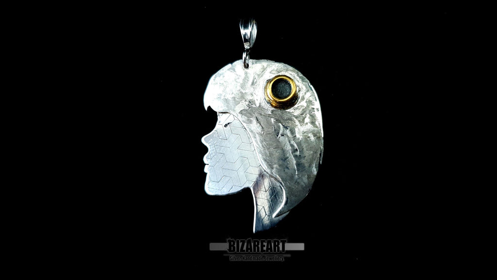 A close-up shot of the pendant highlighting the contrast between the swirling texture of the hair and the geometric laser-engraved pattern on the face.