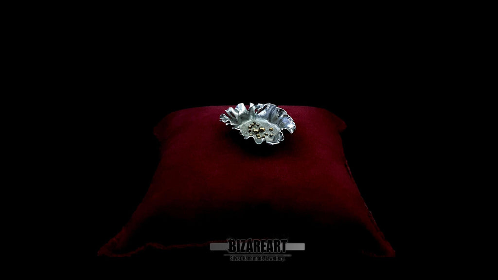 Side profile of the organic silver pendant on a red velvet display, highlighting the depth and sculptural folds of the metal.