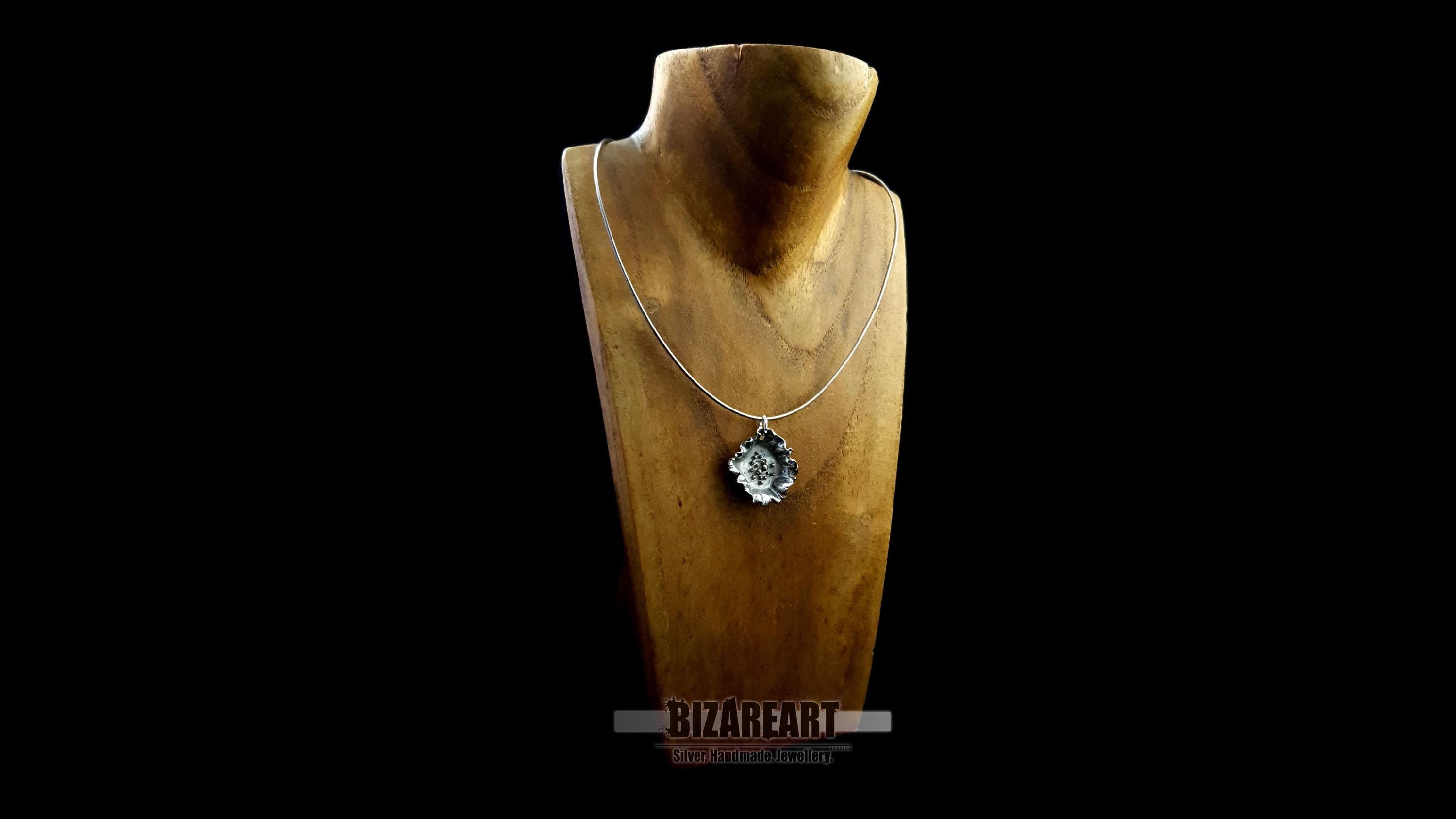 Three-quarter angle of the pendant on a necklace bust, showing how the piece sits and reflects light when worn.