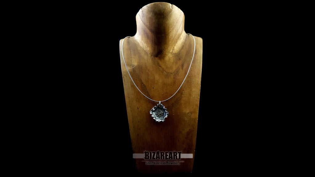 Front view of the dark silver pendant styled on a minimalist silver chain, displayed on a wooden jewelry bust.