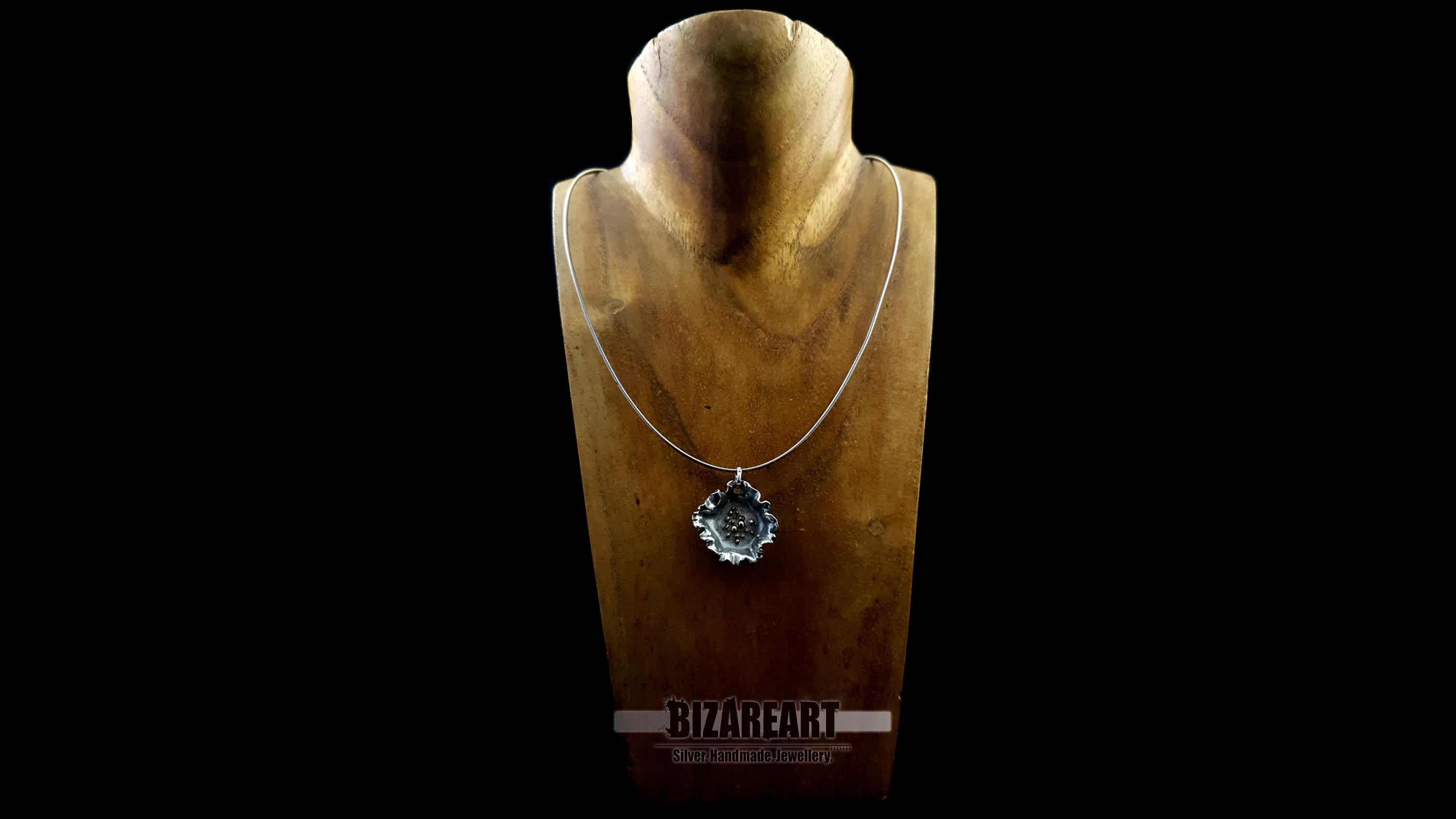 Front view of the dark silver pendant styled on a minimalist silver chain, displayed on a wooden jewelry bust.