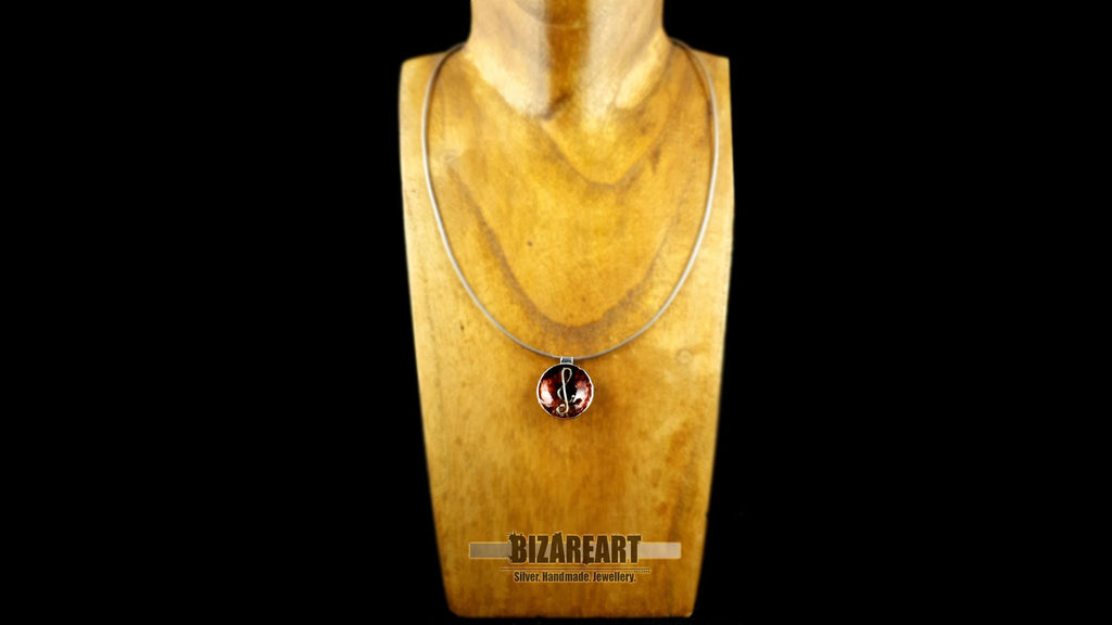 A centered view of the pendant on a black textured surface, focusing on the high-shine rhodium finish and mixed metal contrast.