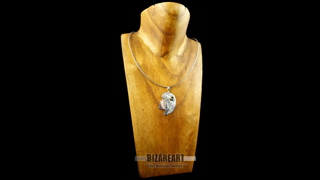 The silver portrait pendant displayed on a delicate silver chain around a wooden jewelry bust to show scale and length.