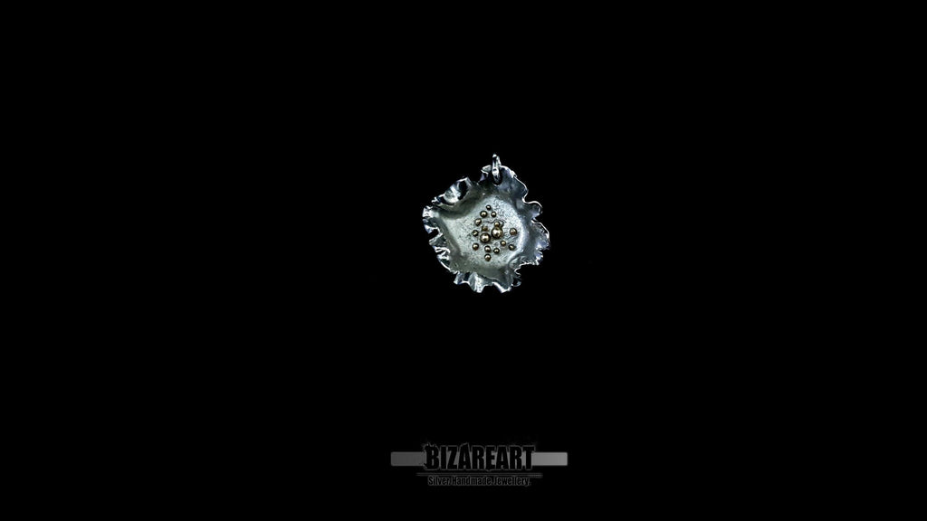 Overhead view of a dark rhodium-plated silver pendant featuring hand-granulated gold beads at the center.