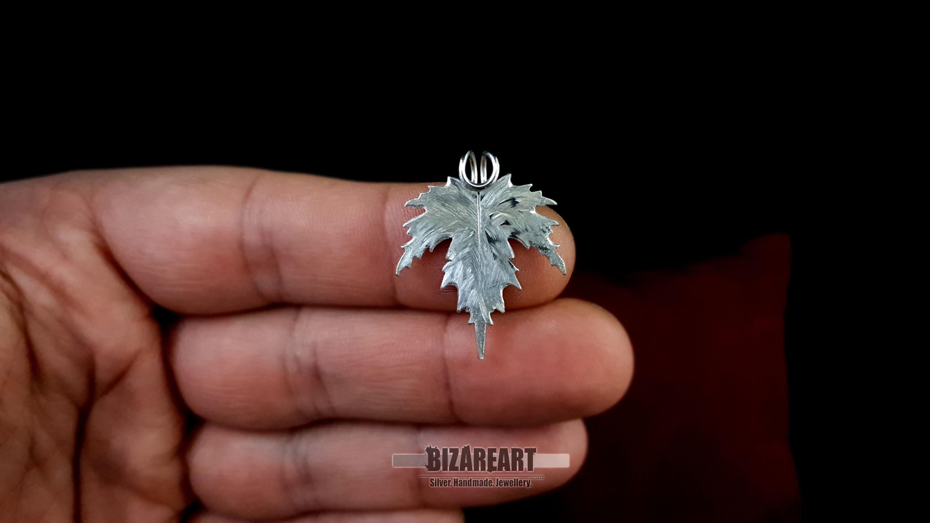Close-up of the silver pendant held in a person's palm to demonstrate the 3.1 cm scale and hand-finished details.