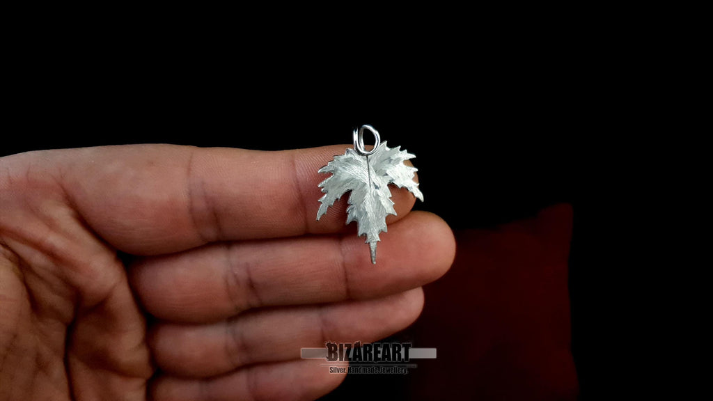 Profile view of the silver leaf being held, showing the depth of the metal carvings and the high-shine rhodium finish.