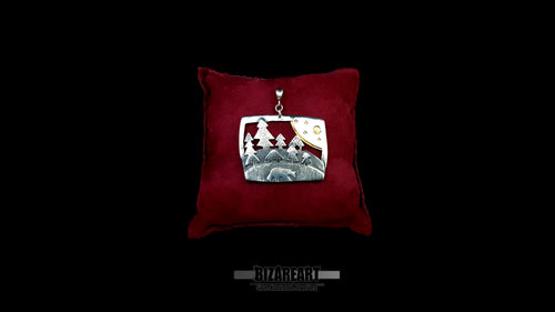 Handcrafted sterling silver bear and forest diorama pendant resting on a luxury crimson red velvet display pillow against a black background.