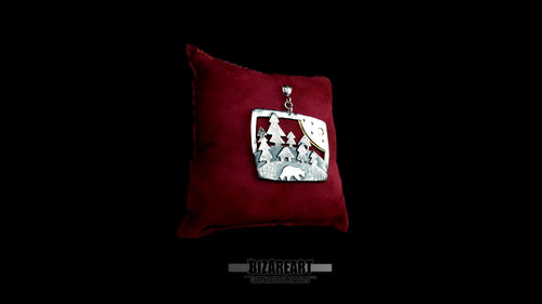 Side perspective view of the 3D multi-layered silver wilderness pendant on a small dark red display cushion, highlighting its substantial thickness.