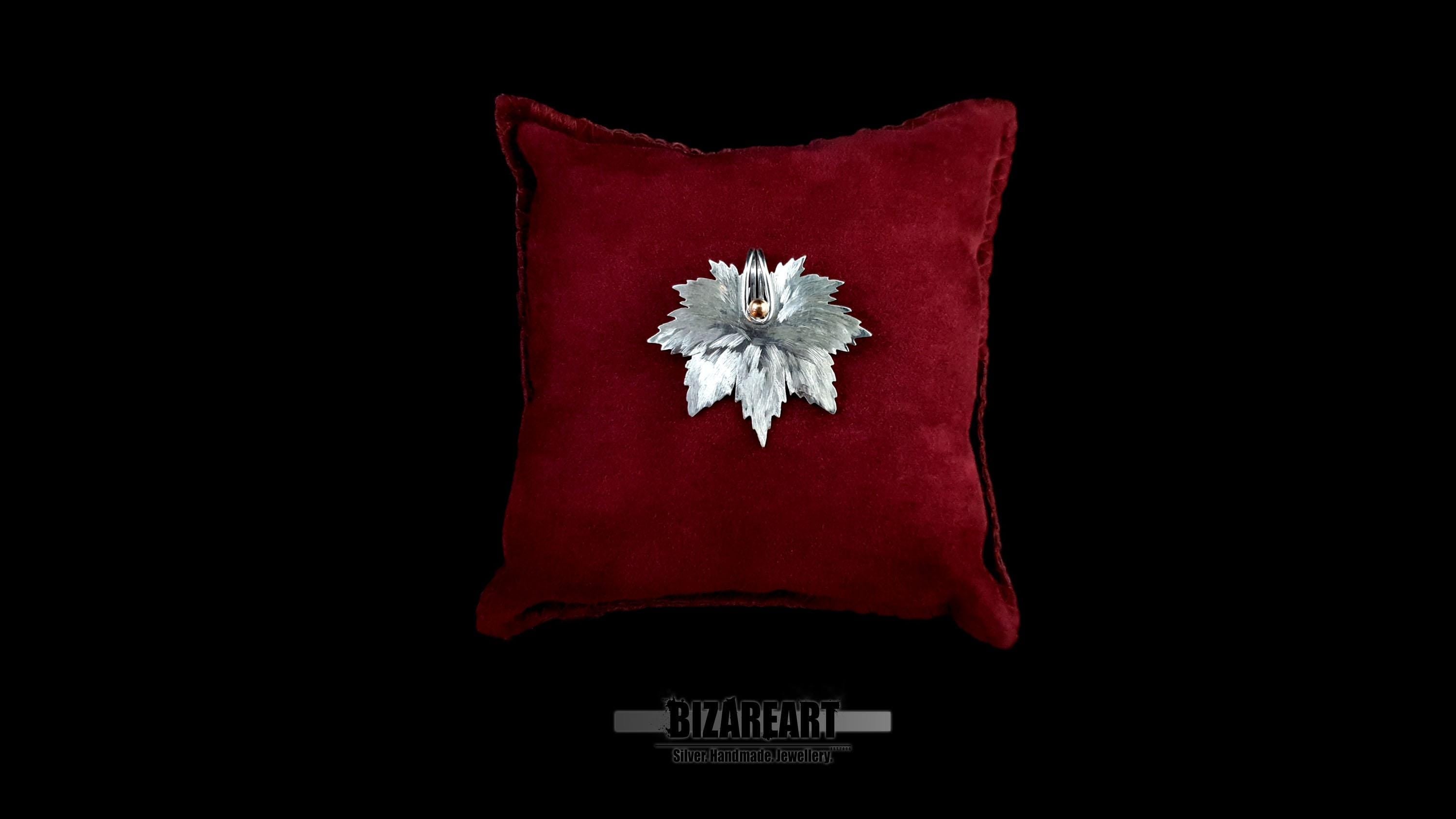 Handcrafted 925 sterling silver maple leaf pendant with mixed-metal rose gold center, displayed on a luxury red velvet cushion.