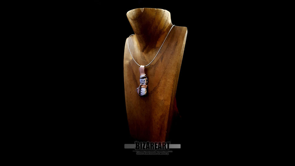 Wide shot of the handcrafted silver and rose gold snowman necklace on a professional display, showcasing its elegant profile and holiday aesthetic.