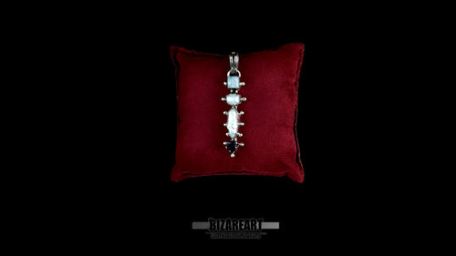 A detailed top-down view of the handcrafted sterling silver Celestial Quad Pendant, featuring four articulated settings with natural moonstone, pearl, and garnet, resting centrally on a plush maroon velvet presentation pillow against a black background.