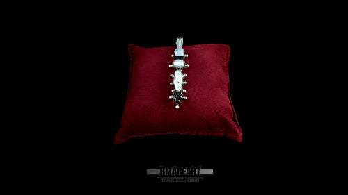 A high-angle studio shot of the sterling silver Celestial Quad Pendant, with its unique stack of four gemstones (moonstone, pearl, garnet), resting on a deep red velvet display cushion against a black backdrop.