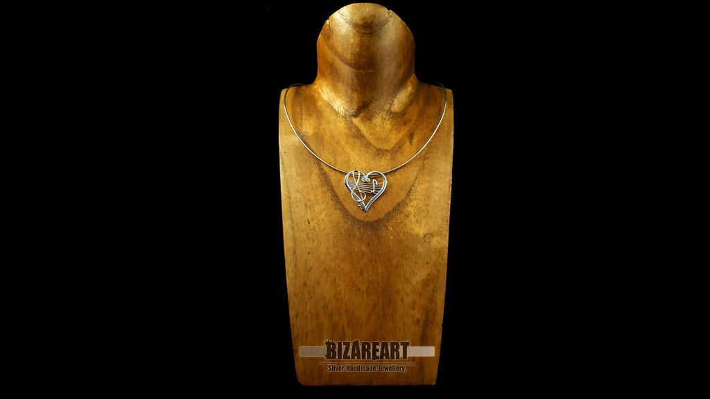 A gold jewelry display bust wearing the sterling silver heart melody pendant on a chain, providing a clear visual reference for how the statement piece sits on the neckline.