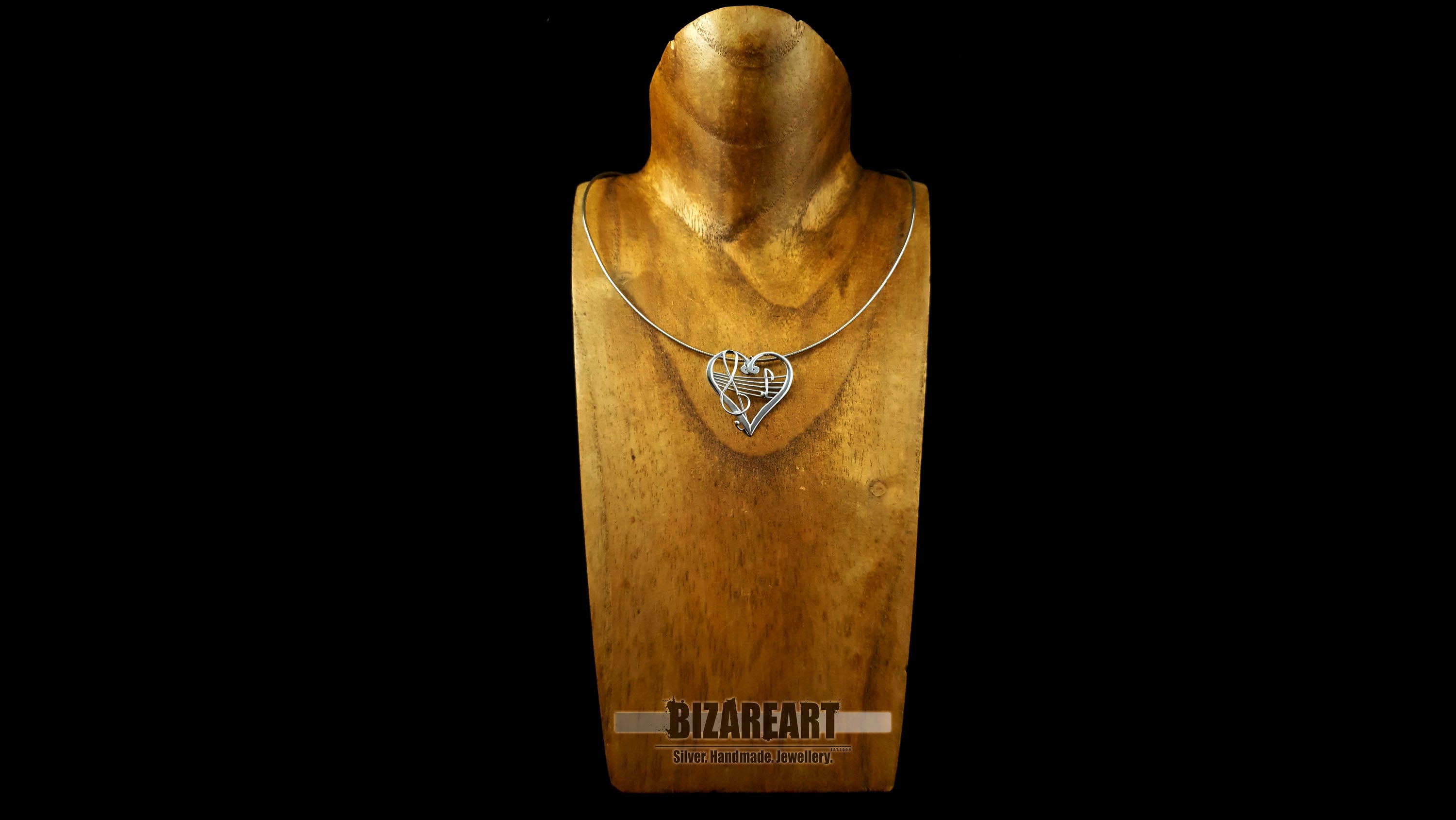 A gold jewelry display bust wearing the sterling silver heart melody pendant on a chain, providing a clear visual reference for how the statement piece sits on the neckline.