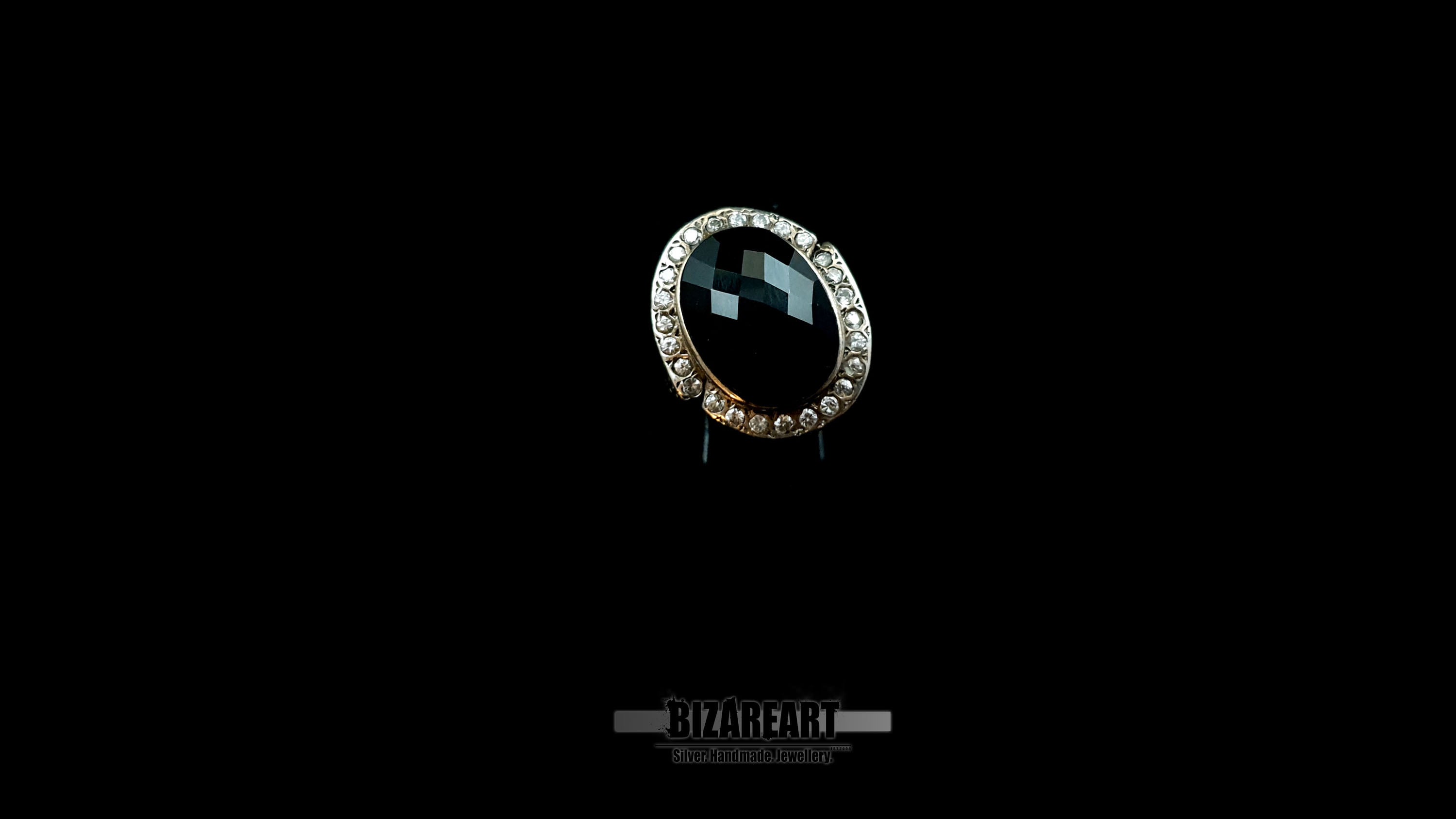 Angled shot of a Bizareart sterling silver ring featuring a large faceted onyx stone, highlighting the depth and light reflection of the facets.