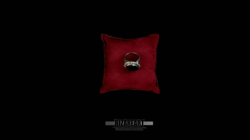 Top-down view of a heavy 14.8g sterling silver onyx ring resting on a luxury red velvet cushion, showcasing the high-polish finish.