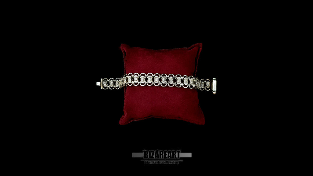 Artisan Bizareart .925 silver link bracelet laid flat across a red display cushion, highlighting the open integrated barrel clasp on the right.