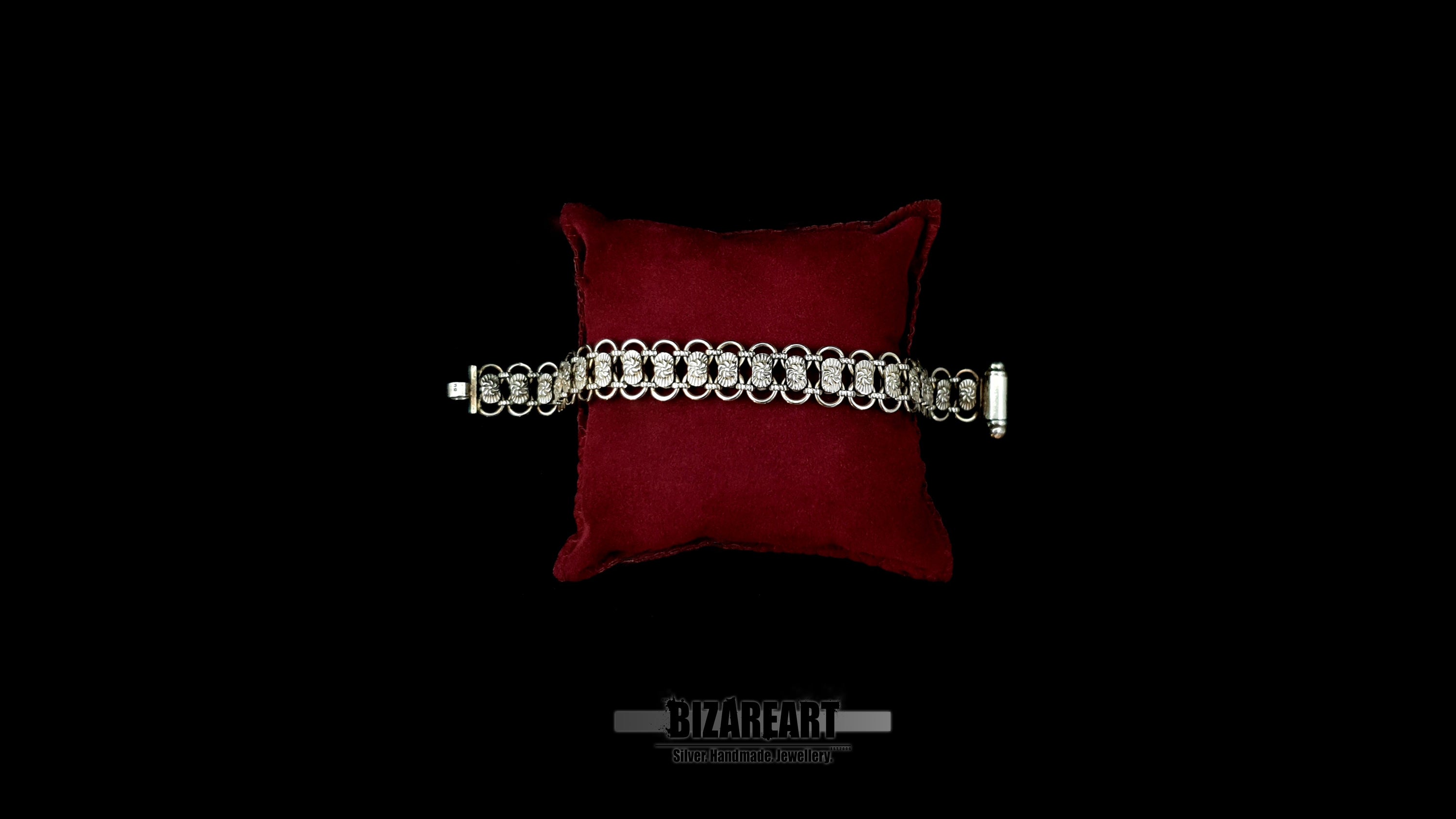 Artisan Bizareart .925 silver link bracelet laid flat across a red display cushion, highlighting the open integrated barrel clasp on the right.