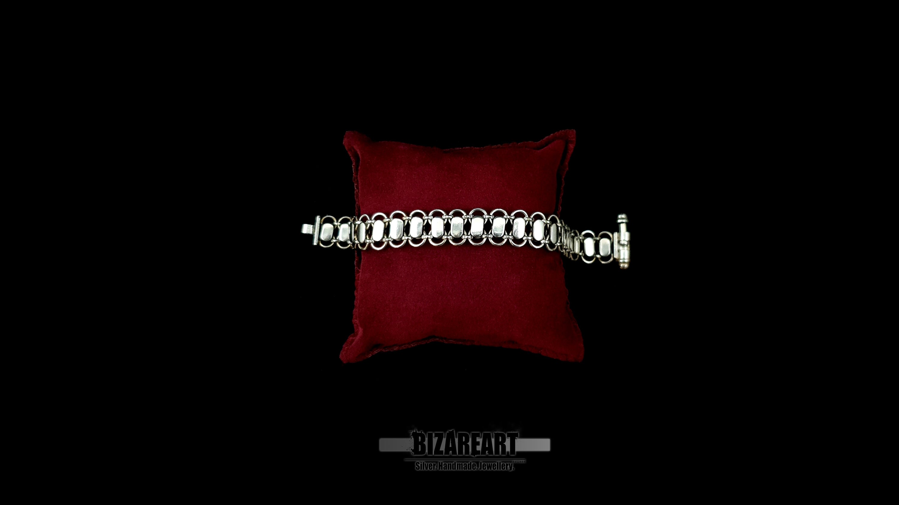 Smooth, mirror-polished reverse side of the Bizareart Byzantium sterling silver link bracelet displayed on a red velvet pillow.