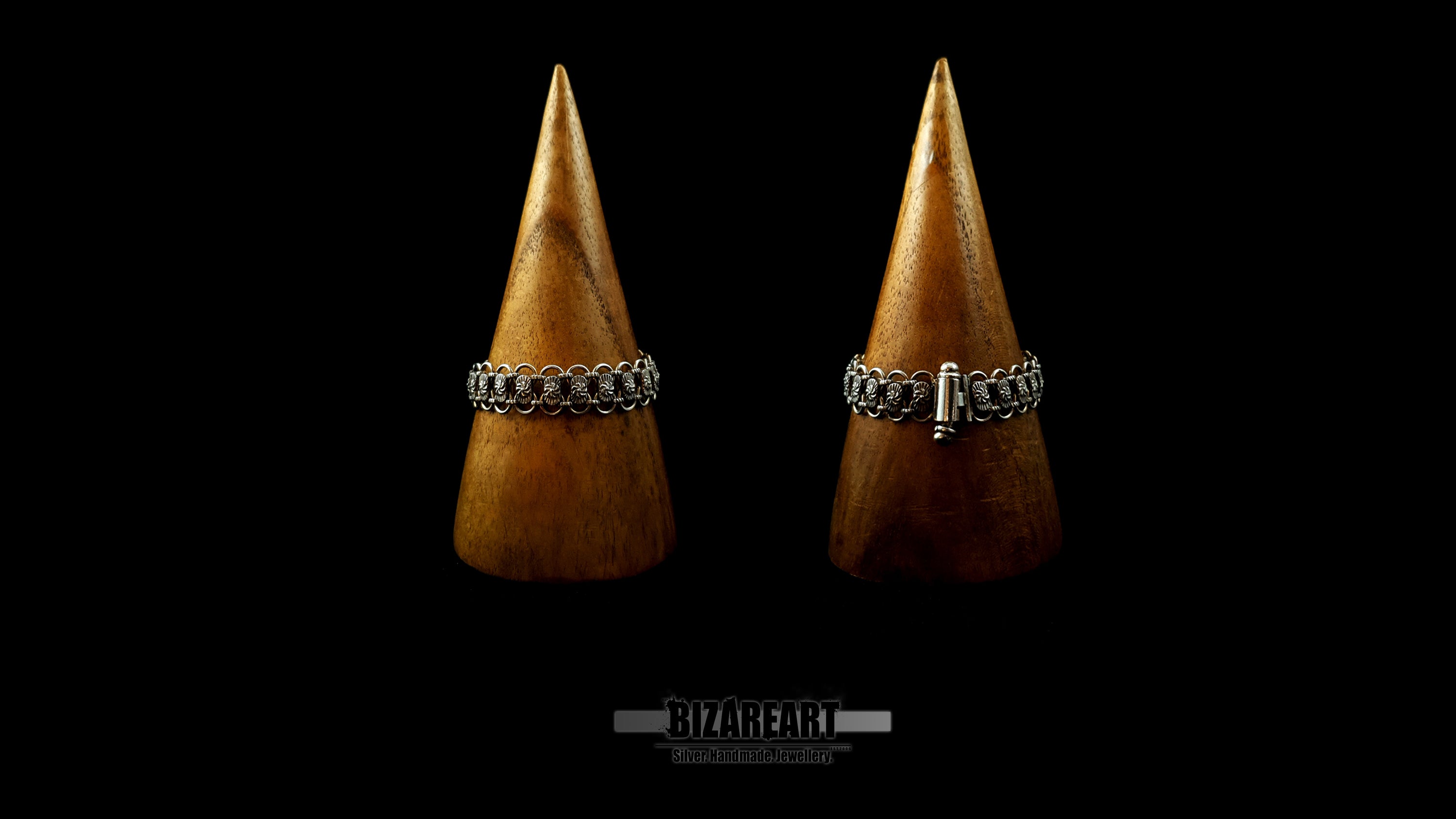 Two wooden cone jewelry displays side-by-side showcasing both the detailed front links and the clean back clasp of the Bizareart silver bracelet.