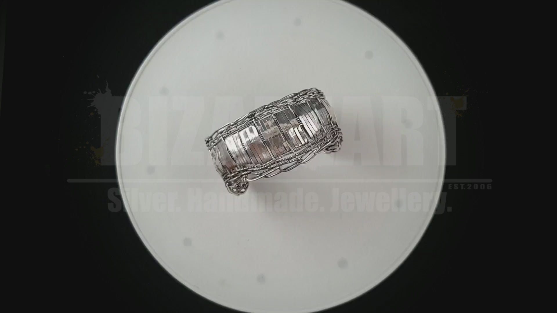 Product video demonstrating how to easily slide the adjustable multilayered silver bracelet onto the wrist and showing the metal's brilliant catch of light under motion.