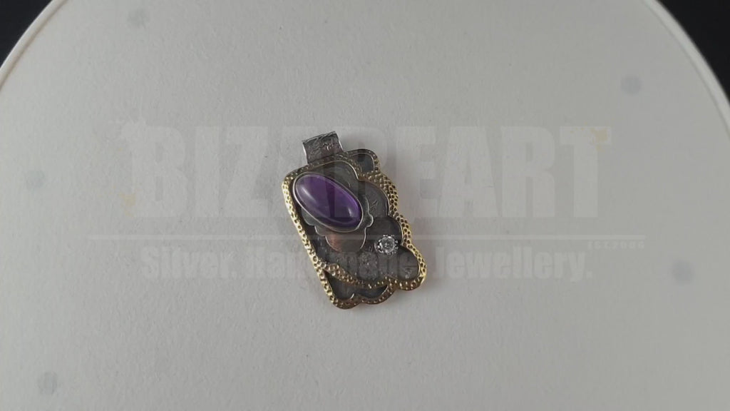 A 360-degree rotating video of the Bizareart silver pendant, showcasing how the light reflects off the faceted Amethyst and Cubic Zirconia while highlighting the rich, sculptural textures of the granulated silver and gold-plated frame.