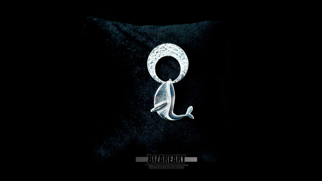 Video demonstration of the handmade kinetic silver pendant, showcasing the free-swinging movement of the whale breaching beneath the hammered crescent moon to highlight the interactive, multi-part design.