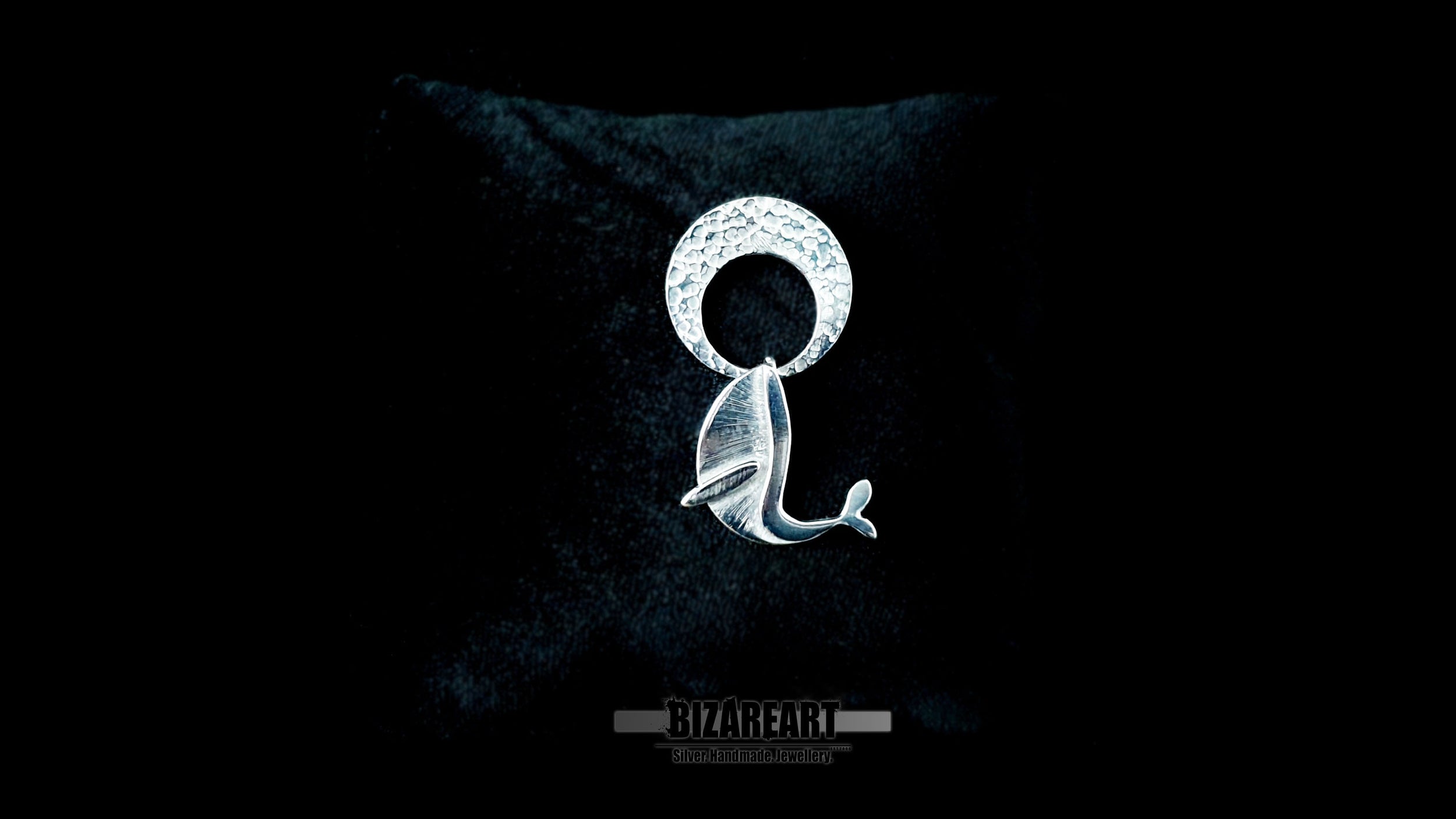 Video demonstration of the handmade kinetic silver pendant, showcasing the free-swinging movement of the whale breaching beneath the hammered crescent moon to highlight the interactive, multi-part design.